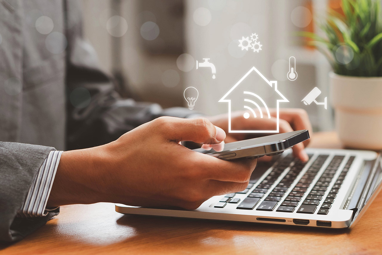 Person using a smart home app on a phone and laptop