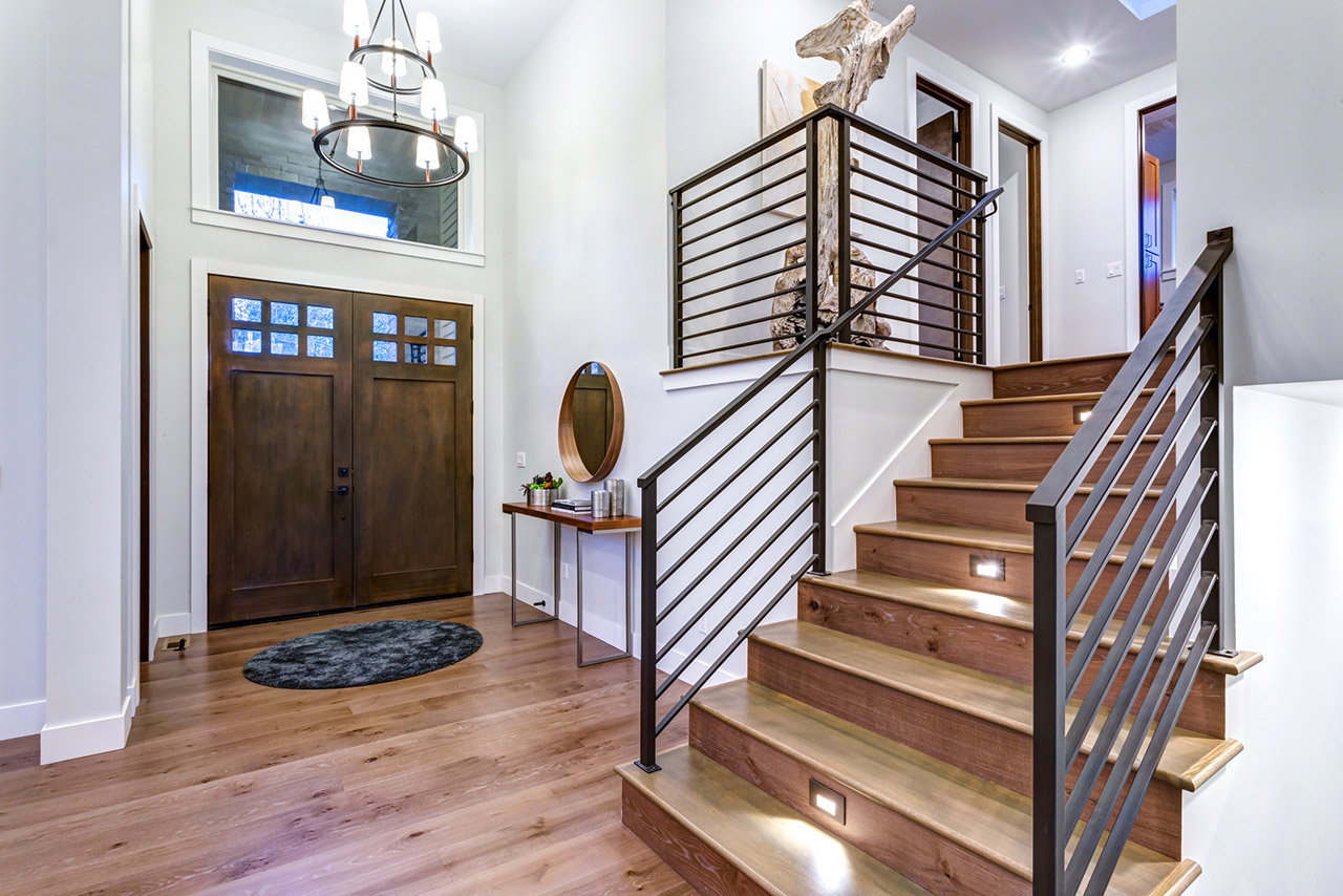 Chic entrance foyer with high ceiling and wide staircase with lights and contemporary railing